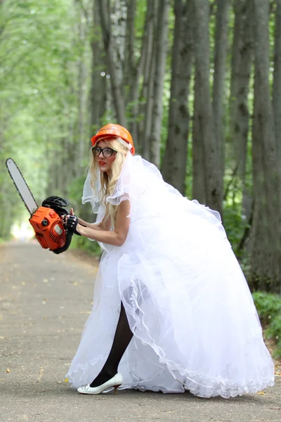Crazy bride with chainsaw in park — Stock Photo, Image