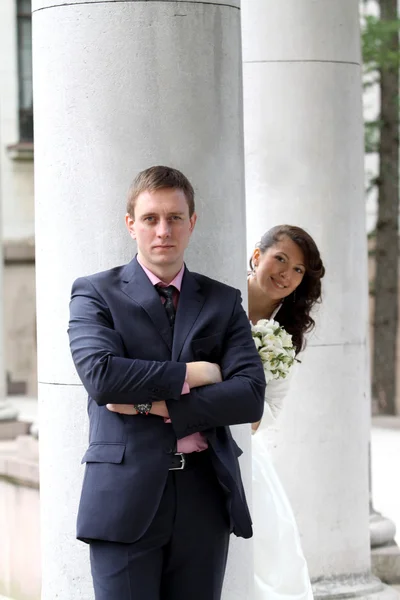 Bride and groom near columns in park — Stock Photo, Image