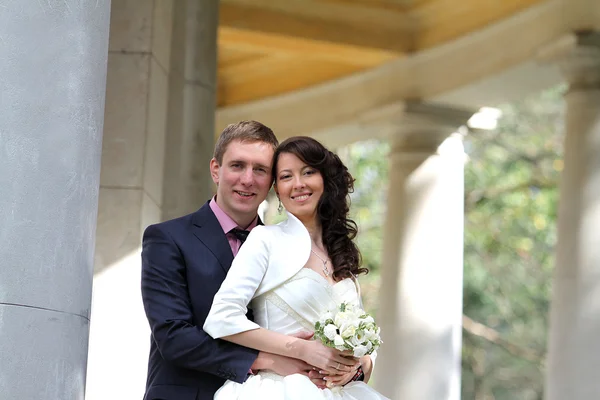 Happy bride and groom near columns — Stock Photo, Image