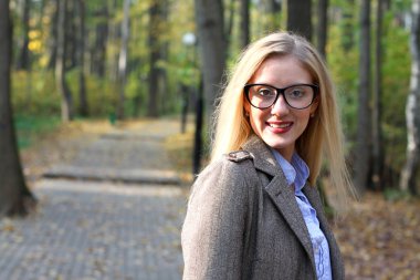 Genç kadın sonbahar parkında yürüyor.