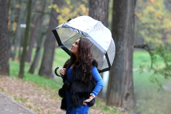 Brunette woman with umbrella walking in park — Stock Photo, Image