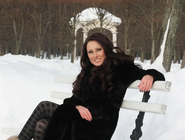 Happy woman sitting on bench in park — Stock Photo, Image