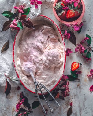 Strawberry ice cream balls with berries and mint leaves in white bowl