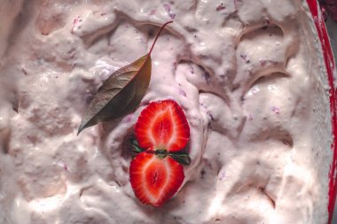Strawberry ice cream balls with berries and mint leaves in white bowl