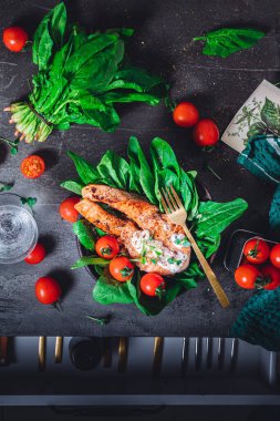 Taze çiğ ıspanak ve kızarmış somon, domates ve krem peynir soslu bir tabak. 