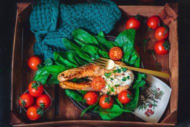 Taze çiğ ıspanak ve kızarmış somon, domates ve krem peynir soslu bir tabak. 