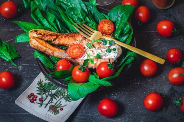 Taze çiğ ıspanak ve kızarmış somon, domates ve krem peynir soslu bir tabak. 