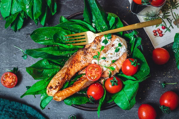 Taze çiğ ıspanak ve kızarmış somon, domates ve krem peynir soslu bir tabak. 