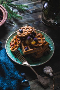 Kruvasan Waffle ya da çilek ve yaban mersini soslu koyu arkaplanda servis edilen Croffle. Kapat, boşluğu kopyala.