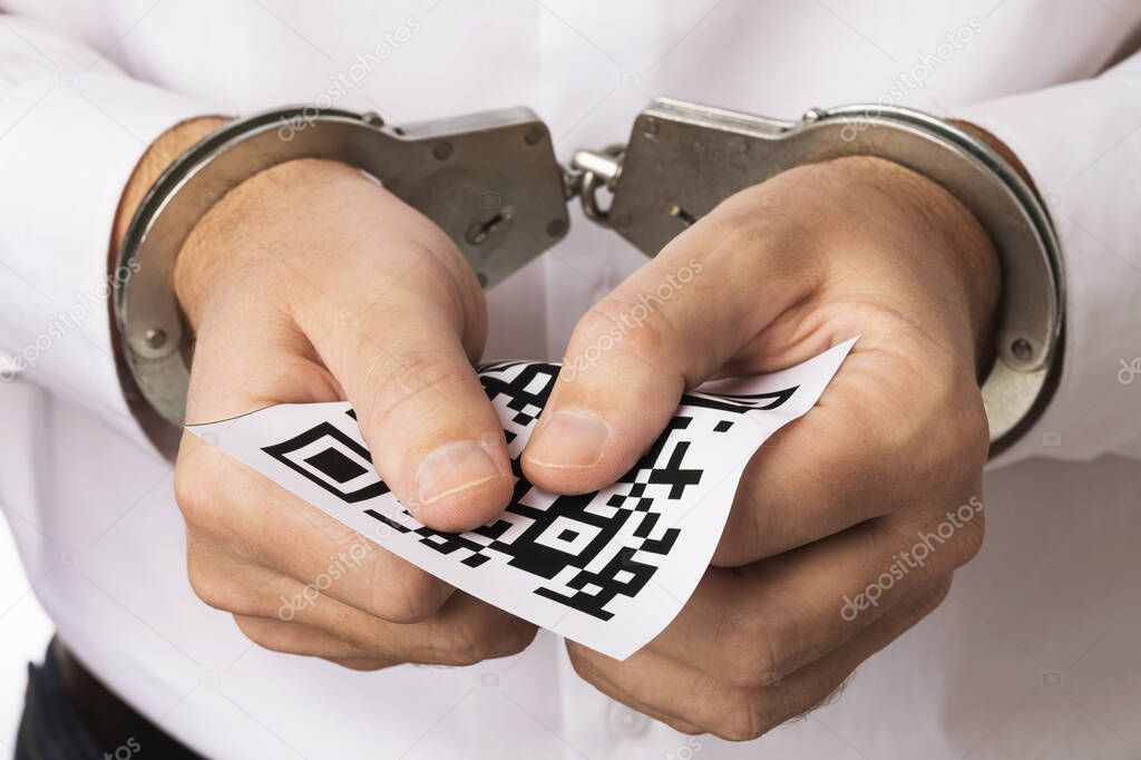 A man in handcuffs holds a sheet with a barcode, the concept of punishment for forgery of QR codes