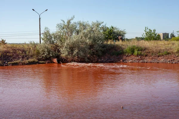 Technical settler of industrial water of mining industry in Kryvyi Rih, Ukraine. Redwater is polluted with iron ore waste. Discharge of process water in the sump after the iron ore beneficiation