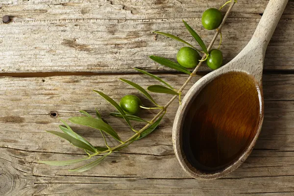 Rama de olivo y una cuchara llena de aceite — Foto de Stock