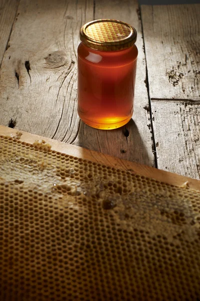 Panal de abeja con miel fresca en un jarrón sobre una mesa de madera . — Foto de Stock