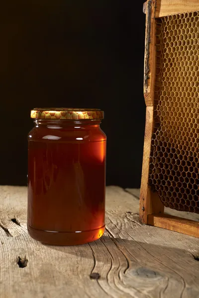 Panal de abeja con miel fresca en un jarrón sobre una mesa de madera . — Foto de Stock