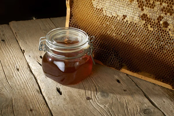 Favo de mel com mel fresco em um vaso na mesa de madeira . — Fotografia de Stock