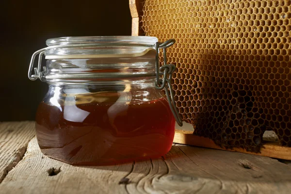 Panal de abeja con miel fresca en un jarrón sobre una mesa de madera . — Foto de Stock