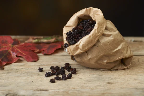 Black raisins in paper bags on a wooden table — Stock Photo, Image