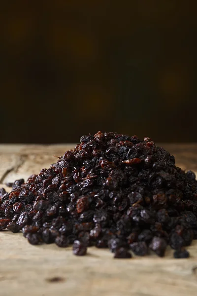 Black raisins over wooden table — Stock Photo, Image