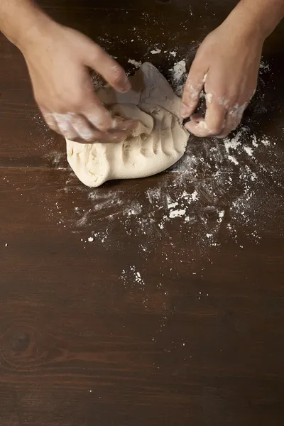 Mains de femme pétrissant pâte sur table en bois — Photo