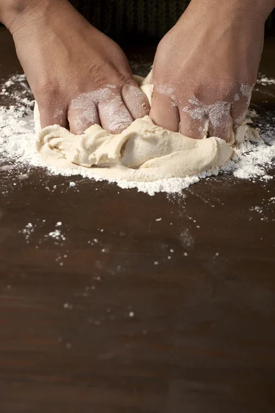 Kvinnans händer knåda degen på träbord — Stockfoto