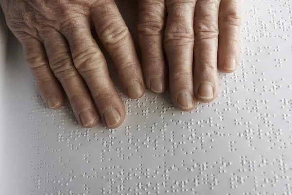 Old womans hands, reading a book with braille language — Stock Photo, Image