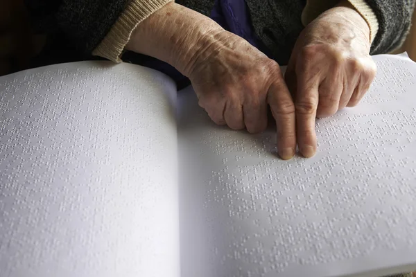 Oude dames handen, lezen van een boek met braille taal — Stockfoto