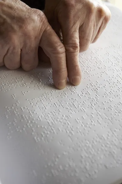 Oude dames handen, lezen van een boek met braille taal — Stockfoto
