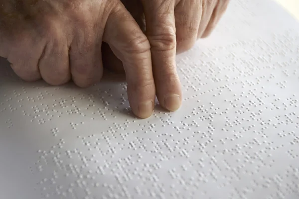 Oude dames handen, lezen van een boek met braille taal — Stockfoto