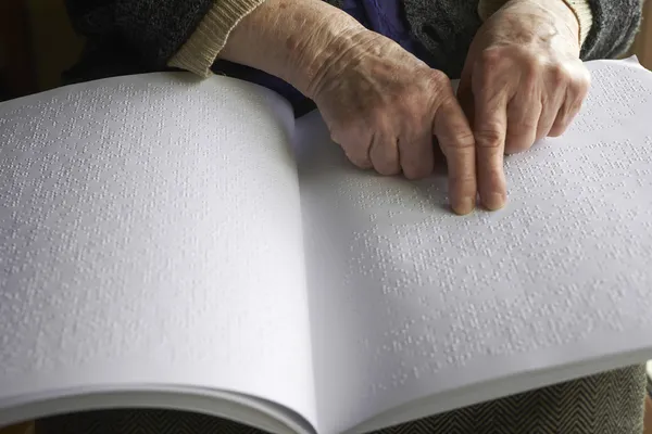 Old womans hands, reading a book with braille language — Stock Photo, Image