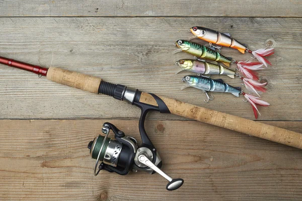 Señuelos de colores con la caña de pescar en el muelle de madera —  Fotos de Stock