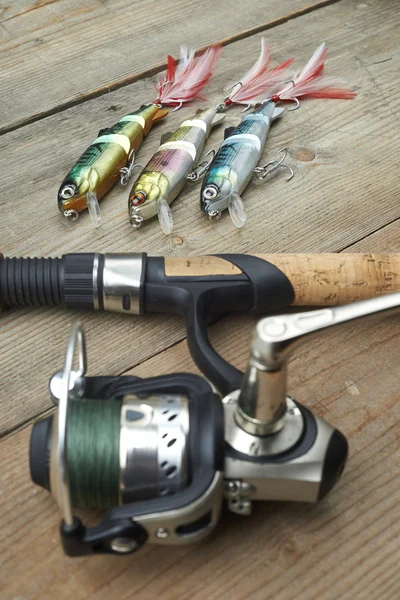 Señuelos de colores con la caña de pescar en el muelle de madera —  Fotos de Stock