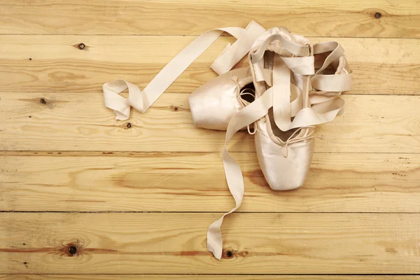 Par de sapatos de balé pointes no chão de madeira — Fotografia de Stock