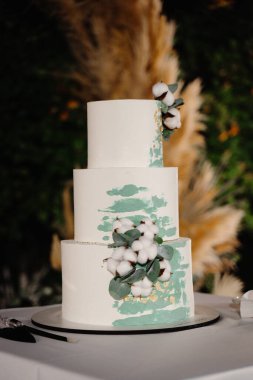 Beyaz çiçekli ve mumlu düğün pastası.