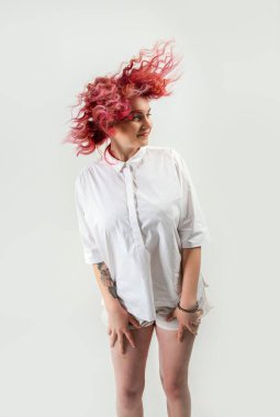 Güzel kızıl saçlı kız beyaz bir arka planda poz veriyor. Yüzünde duygular var.