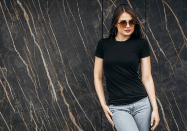 Siyah tişörtlü, güneş gözlüklü şık esmer kız sokakta poz veriyor, kentsel giyim tarzı. Sokak fotoğrafı.