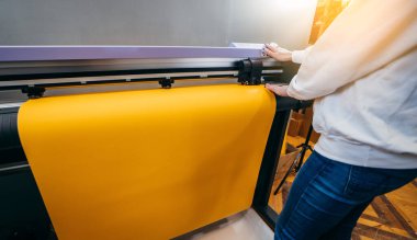 Alarm biçimi yazıcı çizicisinde sarı basılabilir materyali tutan kadın eller. Grafik tasarım ve reklam kavramı.