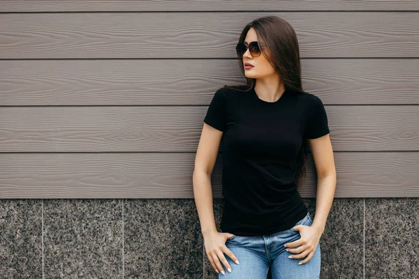 时尚的黑发女孩穿着黑色T恤和太阳镜面对街道 都市服装风格 街头摄影 — 图库照片