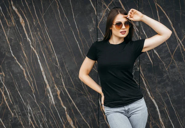 时尚的黑发女孩穿着黑色T恤和太阳镜面对街道 都市服装风格 街头摄影 — 图库照片