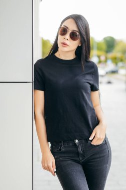 Siyah tişört giyen şık esmer kız sokak ortasında poz veriyor, kentsel giyim tarzı. Sokak fotoğrafı.