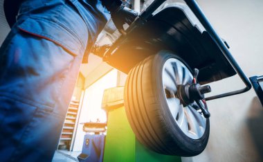 Otomobil tamircisi lastik dengeleme makinesi kullanır ve lastiği döndürür