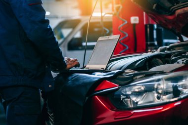 Otomatik elektrikçi, tamir ve onarım için araba motorlarının parçalarını tanımlamak ve kontrol etmek için bir bilgisayar bilgisayarı kullanıyor.