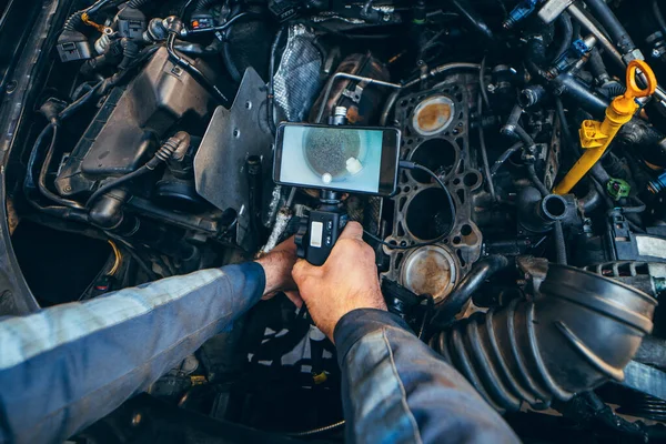 汽车修理工用旋转相机和手机用技术内窥镜检查汽车发动机 发动机头和阀门的修理 — 图库照片
