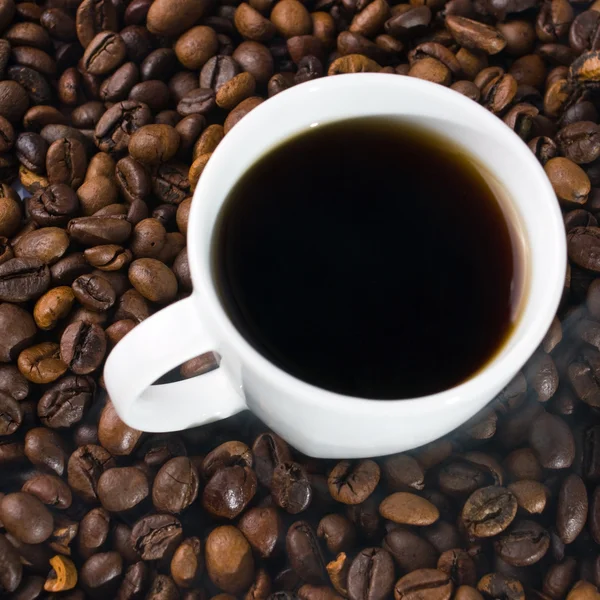 Eine Tasse Kaffee mit Kaffeebohnen als Hintergrund — Stockfoto