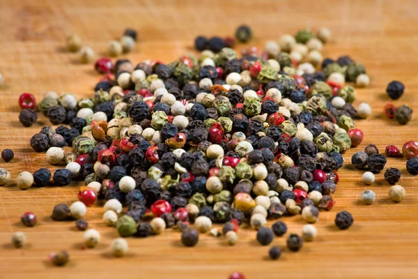 Peppercorns on a wooden board — Stock Photo, Image