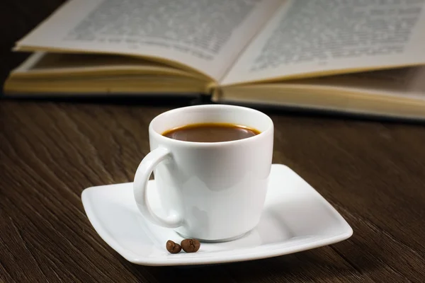 Черный крепкий кофе на столе и чтение книги — стоковое фото