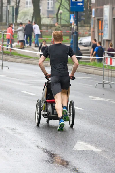 КРАКОВ, ПОЛЬША - 28 апреля: Краковский марафон. Владислав Вачулец с сыном в инвалидной коляске на улицах города 28 апреля 2013 года в Кракове, Польша — стоковое фото
