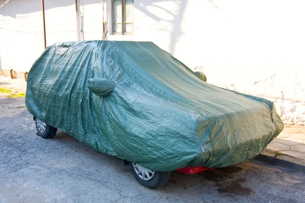 Un coche aparcado con cubierta protectora —  Fotos de Stock