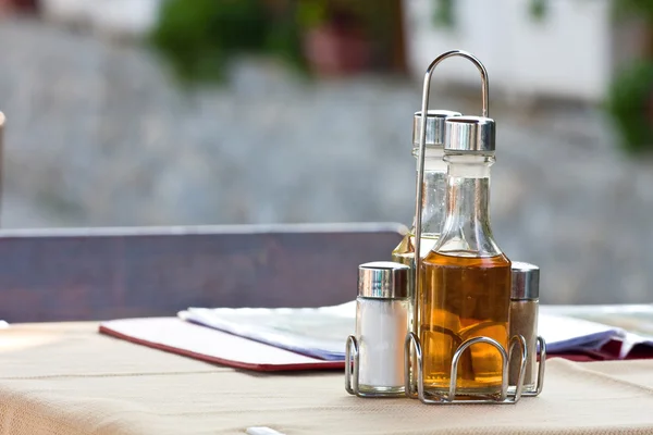 Flessen met olijf olie, azijn, zout en peper op tafel in restaurant — Stockfoto