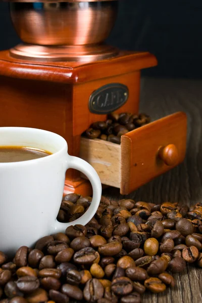 Starožitný mlýnek na kávu, kávová zrna a šálek kávy. — Stock fotografie