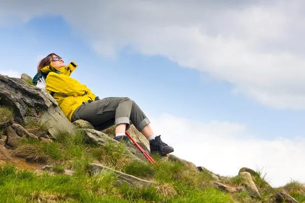 Senderista con mochila relajándose en una roca y mirando al horizonte —  Fotos de Stock